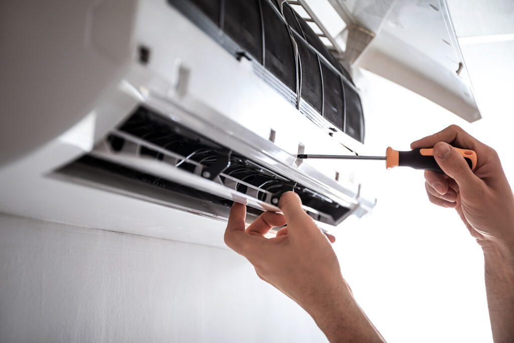 A close up picture of a technician screwing in a part of a ductless air conditioning unit