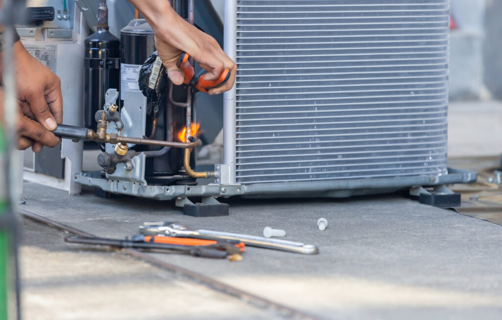 A picture of a technician repairing an air handler of an outside unit