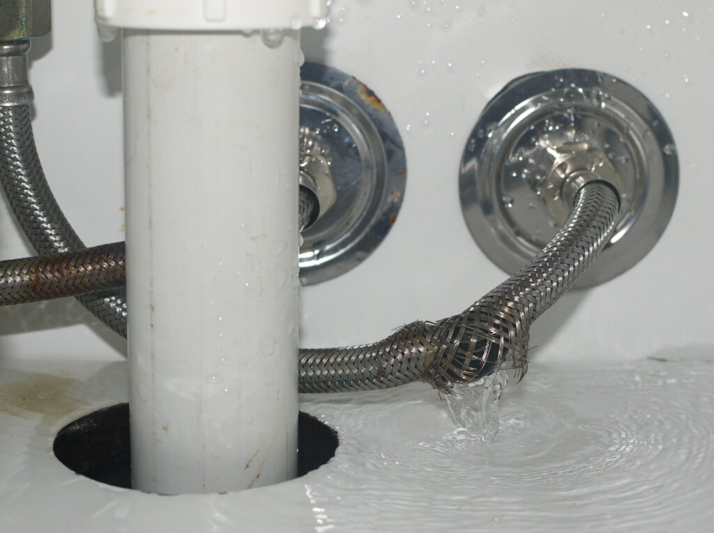 Ruptured hose leaking water in bathroom